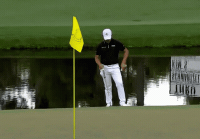 A Man Standing On A Golf Course With A Yellow Flag GIF