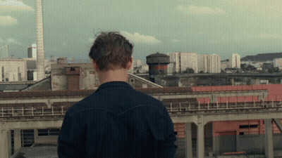 a man standing on a rooftop looking at a city