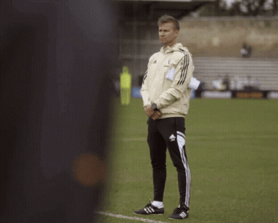 A Man Standing On A Soccer Field Wearing Adidas Pants GIF