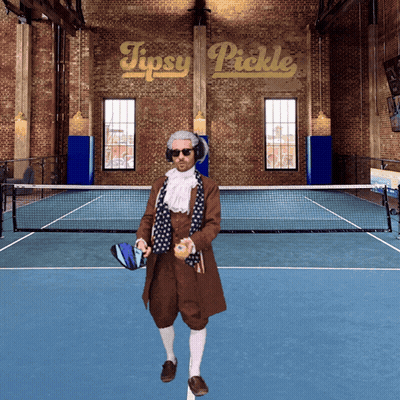 A Man Standing On A Tennis Court With A Sign That Says Tipsy Pickle Behind Him GIF
