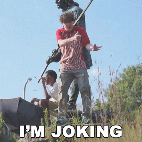 a man standing on top of a statue with the words " i 'm joking " written below him