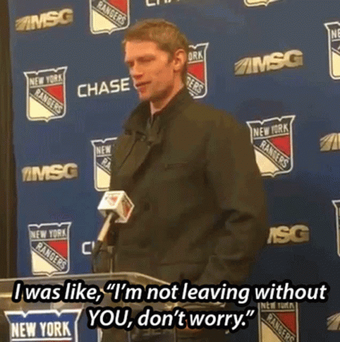 A Man Stands At A Podium With A Microphone In Front Of A Wall With New York Rangers Logos On It GIF