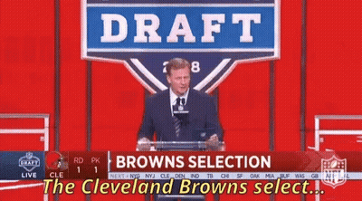 A Man Stands At A Podium With A Sign That Says Draft Browns Selection GIF
