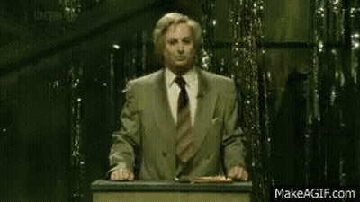 A Man Stands At A Podium With A Sign That Says " Remain Indoors " GIF