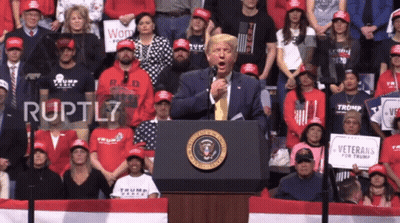 A Man Stands At A Podium With A Sign That Says Veterans For Trump In Front Of Him GIF