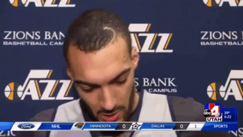 A Man Stands In Front Of A Banner That Says Zions Bank Campus GIF