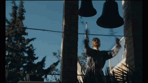 A Man Stands In Front Of A Bell Tower GIF