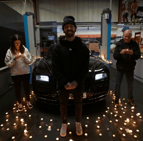 A Man Stands In Front Of A Black Car With A License Plate That Says G6 GIF