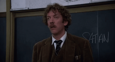 A Man Stands In Front Of A Blackboard With The Words Listen I 'M Not Joking Written On It GIF
