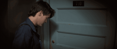 A Man Stands In Front Of A Blue Door With The Number 710 On It GIF