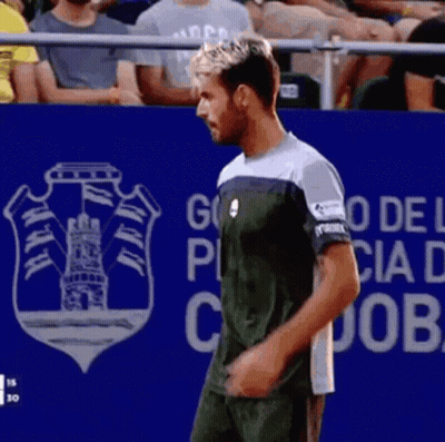 A Man Stands In Front Of A Blue Wall That Says Go Del Puebla GIF