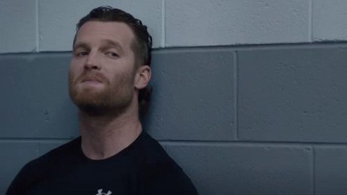 A Man Stands In Front Of A Brick Wall With The Words Hell Yeah Above Him GIF