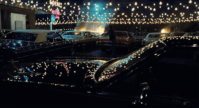 A Man Stands In Front Of A Burning Car In A Parking Lot With A Sign That Says Stop GIF
