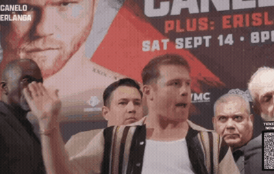 A Man Stands In Front Of A Canelo Advertisement GIF