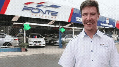 A Man Stands In Front Of A Car Dealership Called Fonte GIF