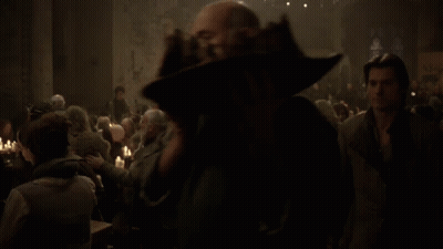 A Man Stands In Front Of A Crowd Of People Sitting At Tables GIF