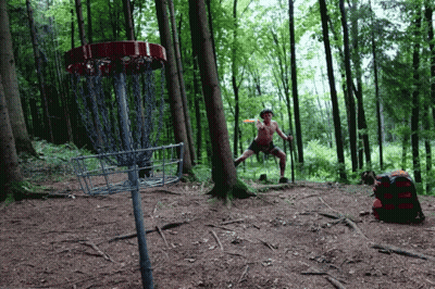 A Man Stands In Front Of A Disc Golf Basket GIF