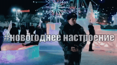 A Man Stands In Front Of A Display Of Ice Sculptures With The Hashtag # Новогодние Настроение Written Above Him GIF