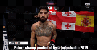 A Man Stands In Front Of A Flag With The Words Future Champ Predicted By @Ludochad In 2019 On The Bottom GIF