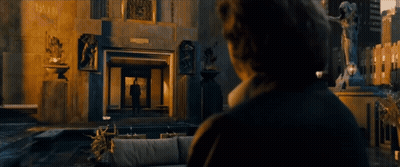 A Man Stands In Front Of A Fountain In Front Of A Large Building GIF