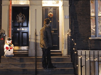 A Man Stands In Front Of A House With The Number 21 On The Front Door GIF