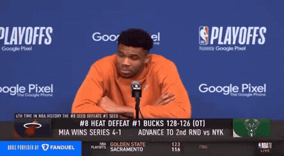 A Man Stands In Front Of A Microphone In Front Of A Screen That Says Playoffs On It GIF