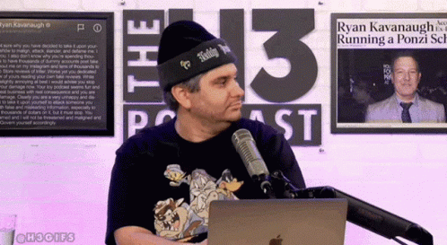 A Man Stands In Front Of A Microphone In Front Of A Sign That Says 13 Podcast GIF