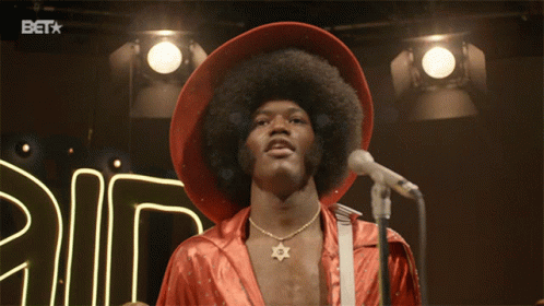 A Man Stands In Front Of A Microphone With A Bet Logo In The Background GIF