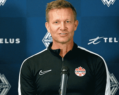 A Man Stands In Front Of A Microphone With A Canada Logo On His Chest GIF