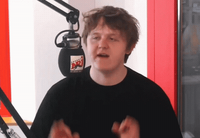 A Man Stands In Front Of A Microphone With A Sticker On It That Says Nrj GIF