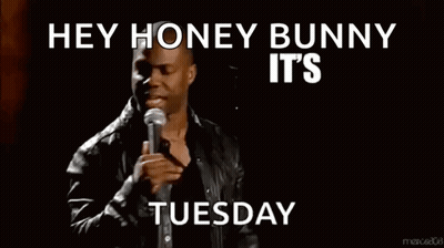 A Man Stands In Front Of A Microphone With The Words Hey Honey Bunny It 'S About To Go Down Tuesday Below Him GIF