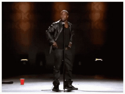 A Man Stands In Front Of A Microphone With The Words " Look Look Look " Behind Him GIF