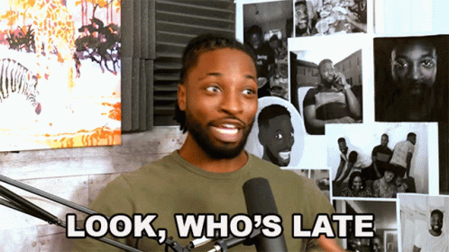 A Man Stands In Front Of A Microphone With The Words Look Who 'S Late Below Him GIF