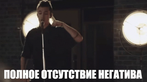 A Man Stands In Front Of A Microphone With The Words " Полное Отсутствие Негатива " Below Him GIF