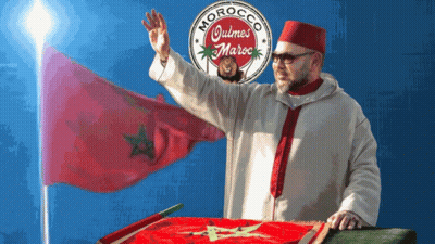 A Man Stands In Front Of A Morocco Quimes Maroc Logo GIF
