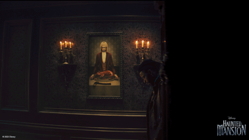 A Man Stands In Front Of A Painting Of A Man In A Tuxedo With Candles In A Haunted Mansion Room GIF