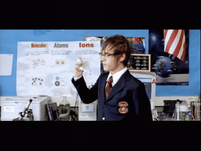 A Man Stands In Front Of A Poster About Molecules And Atoms GIF