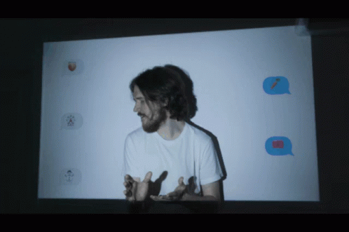 A Man Stands In Front Of A Projector Screen With Emojis Projected GIF