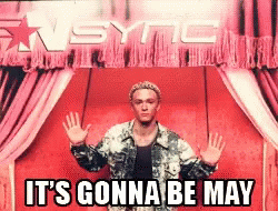 A Man Stands In Front Of A Red Curtain With The Words It 'S Gonna Be May GIF
