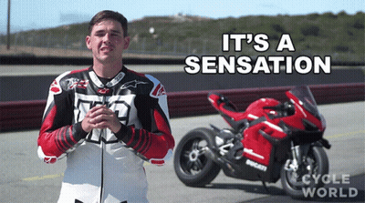 A Man Stands In Front Of A Red Ducati Motorcycle With The Words It 'S A Sensation Written Above Him GIF