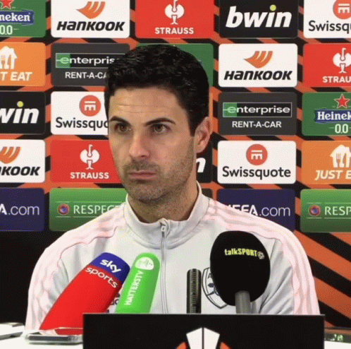 A Man Stands In Front Of A Row Of Advertisements Including Bwin And Hankook GIF