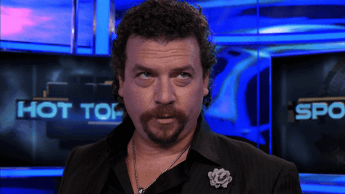 A Man Stands In Front Of A Screen That Says " Hot Top " GIF