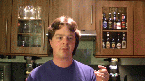A Man Stands In Front Of A Shelf Full Of Beer GIF