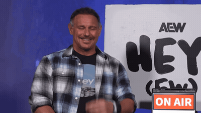 A Man Stands In Front Of A Sign That Says Aew Hey GIF