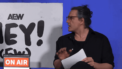 A Man Stands In Front Of A Sign That Says Aew On It GIF