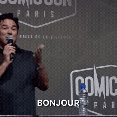 A Man Stands In Front Of A Sign That Says Comic Con Paris GIF