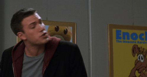 A Man Stands In Front Of A Sign That Says Enock Survey Says GIF