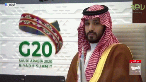 A Man Stands In Front Of A Sign That Says G20 Saudi Arabia 2020 GIF