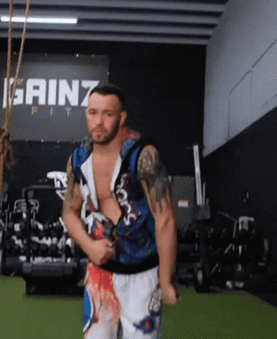 A Man Stands In Front Of A Sign That Says Gainz GIF