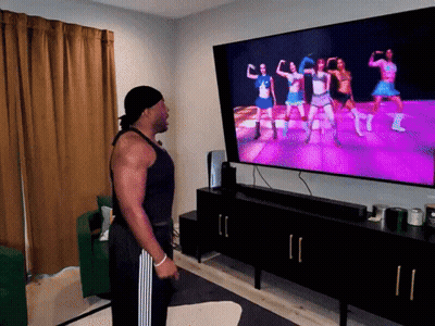 A Man Stands In Front Of A Television Watching A Video GIF